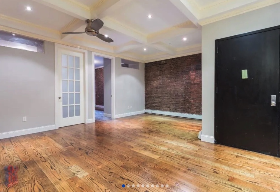 apartment photo of empty room with ceiling fan, doors, and exposed brick walls