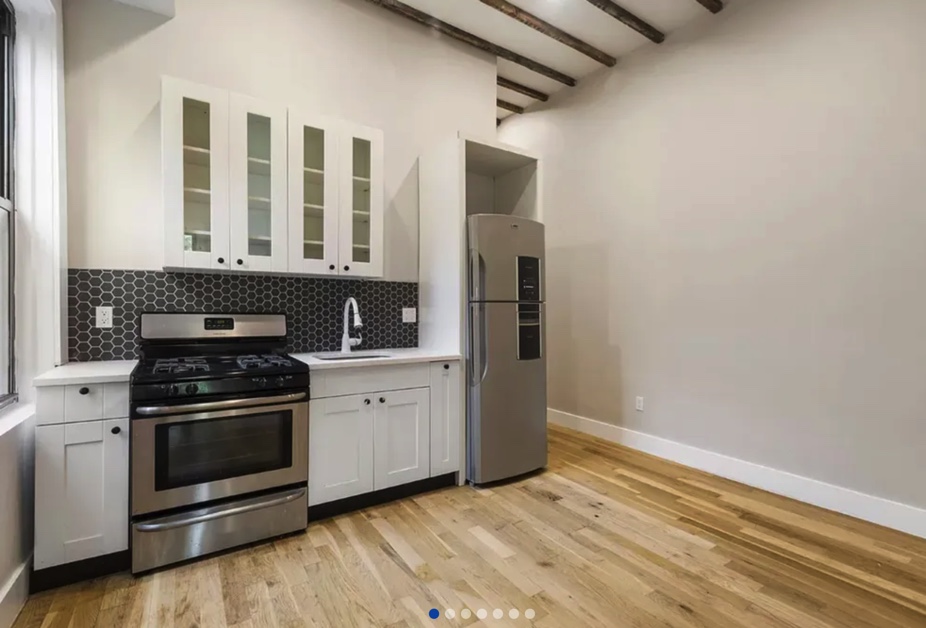 apartment listing photo of empty room and kitchen