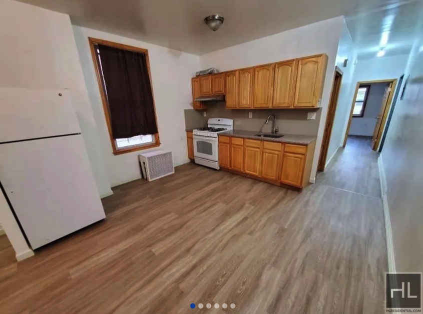 apartment listing photo of empty room and kitchen