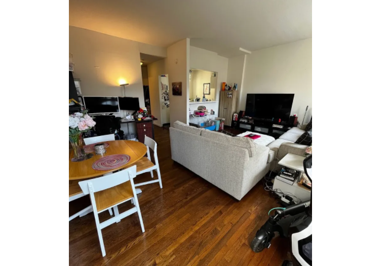 apartment photo of living room with couch, tv, dining table and kitchen in the background