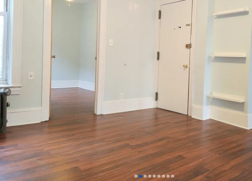 apartment listing photo of empty room with windows and front entrance