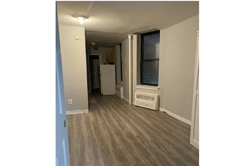 apartment listing photo of empty hallway with kitchen in the background