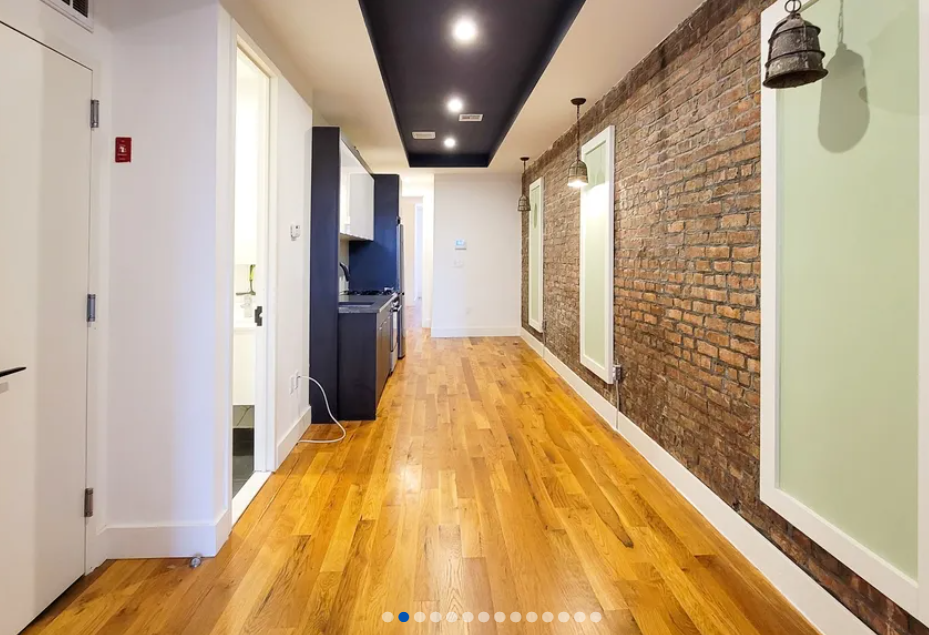 apartment listing photo of an apartment hallway and kitchen with doors to additional rooms