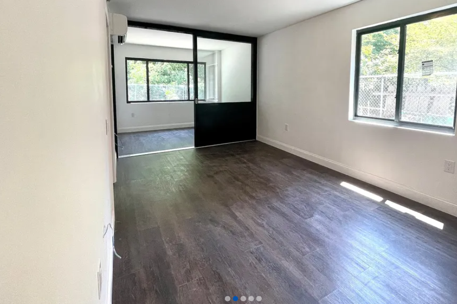 apartment listing photo of empty room with sliding doors and windows
