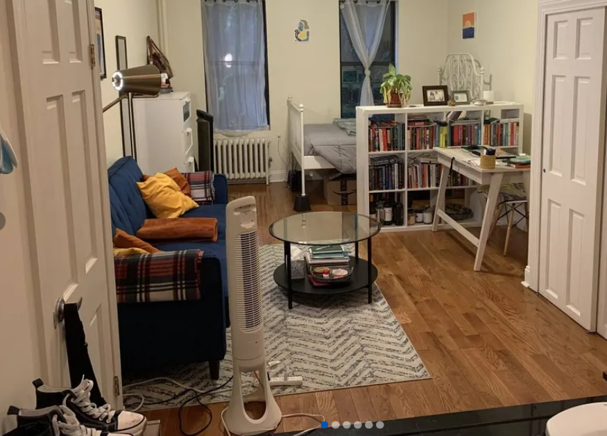photo of furnished studio living room with couch, coffee table, and bed