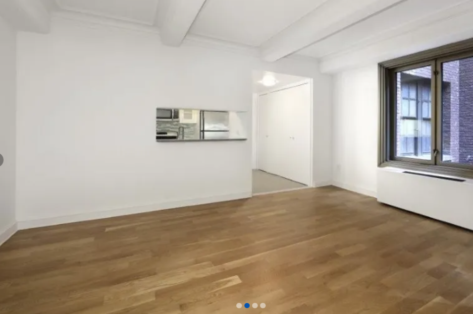 apartment photo of empty room with windows and a separate kitchen