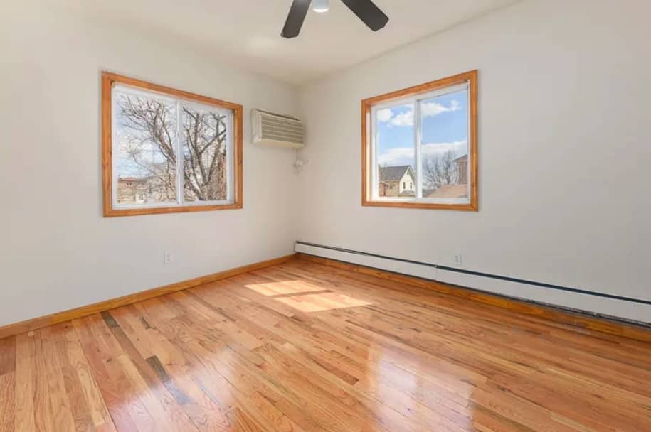 empty room with two windows and hardwood flooring