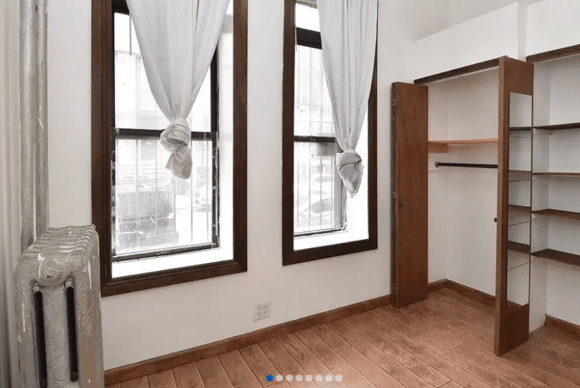 empty living room with windows, radiator, and closet space