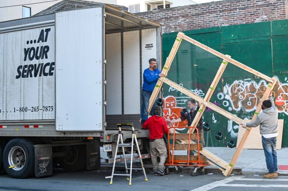 Men moving a large wood frame into a moving truck