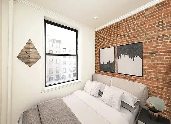 bedroom with exposed brick and window